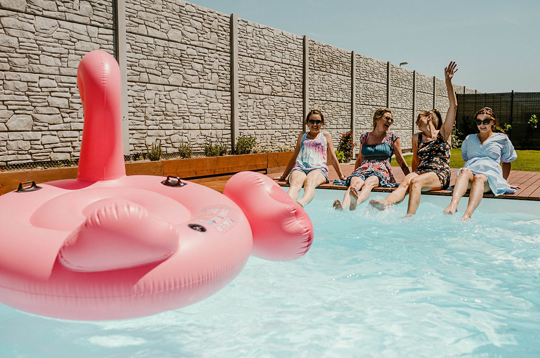 Familie sitzt am Pool im Garten